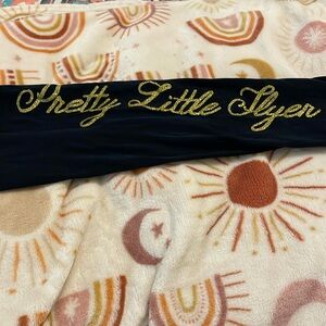 “Pretty Little Flyer” leggings. Black with gold lettering. Size small.